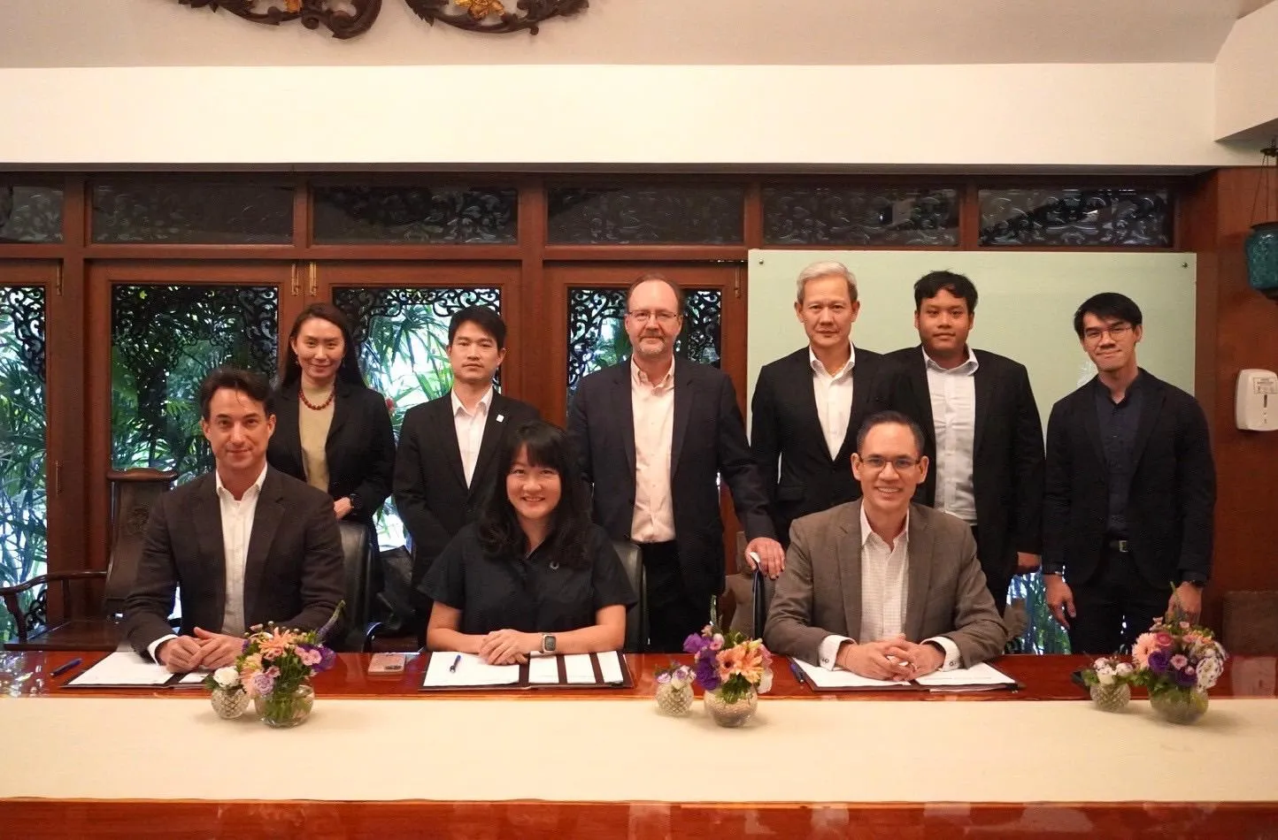 Executives from ddx, AMATA and B.Grimm seated and standing behind the signing table
