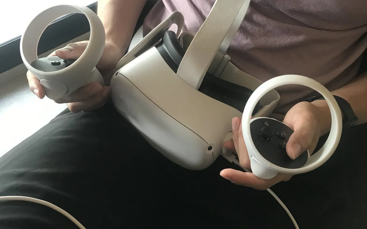 Hands holding a white virtual reality headset and its two controllers