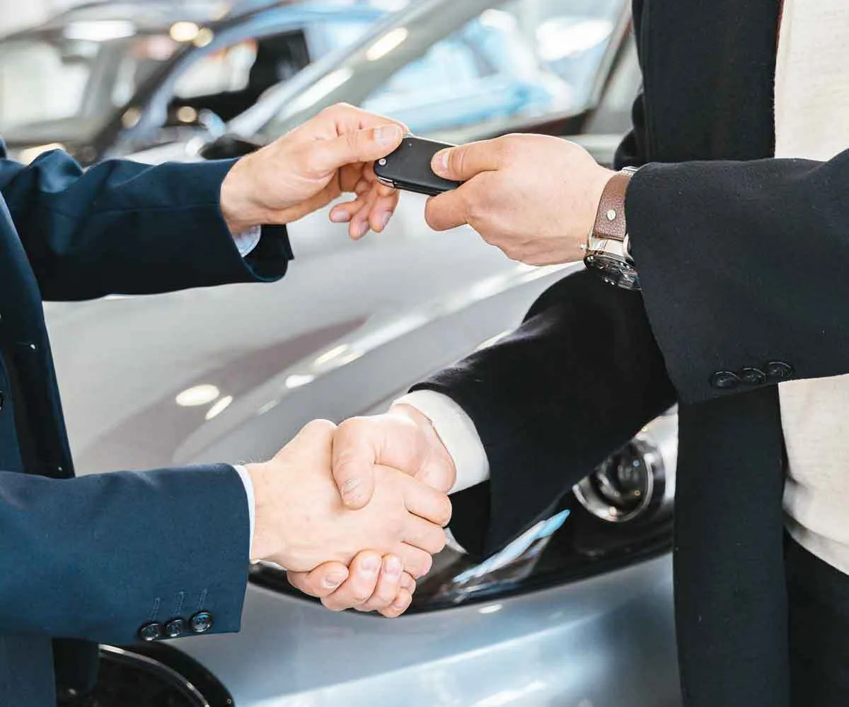Handing over car keys and shaking hands in a showroom