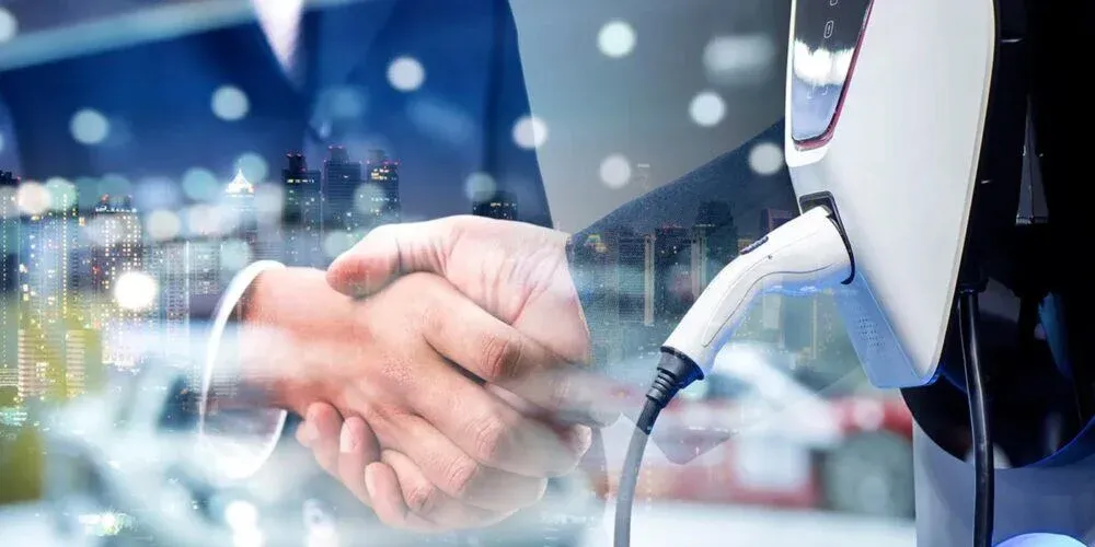 A handshake in front of an electric vehicle charger