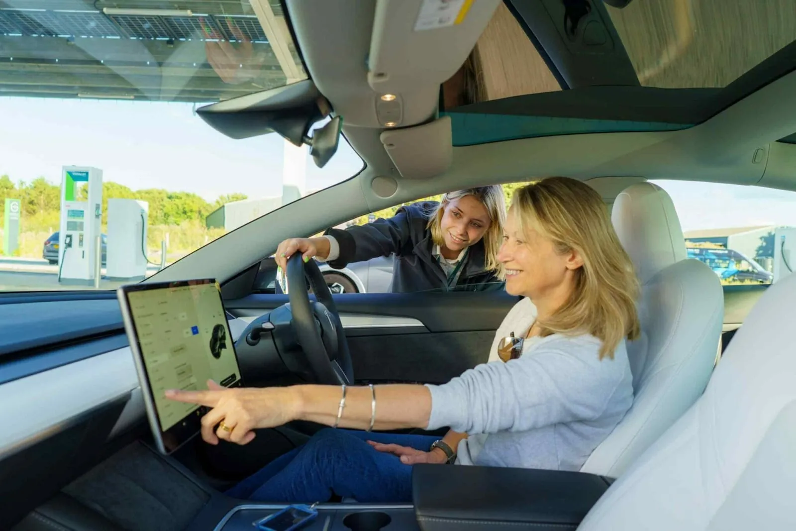 A sales advisor showing a customer the touchscreen in an electric car