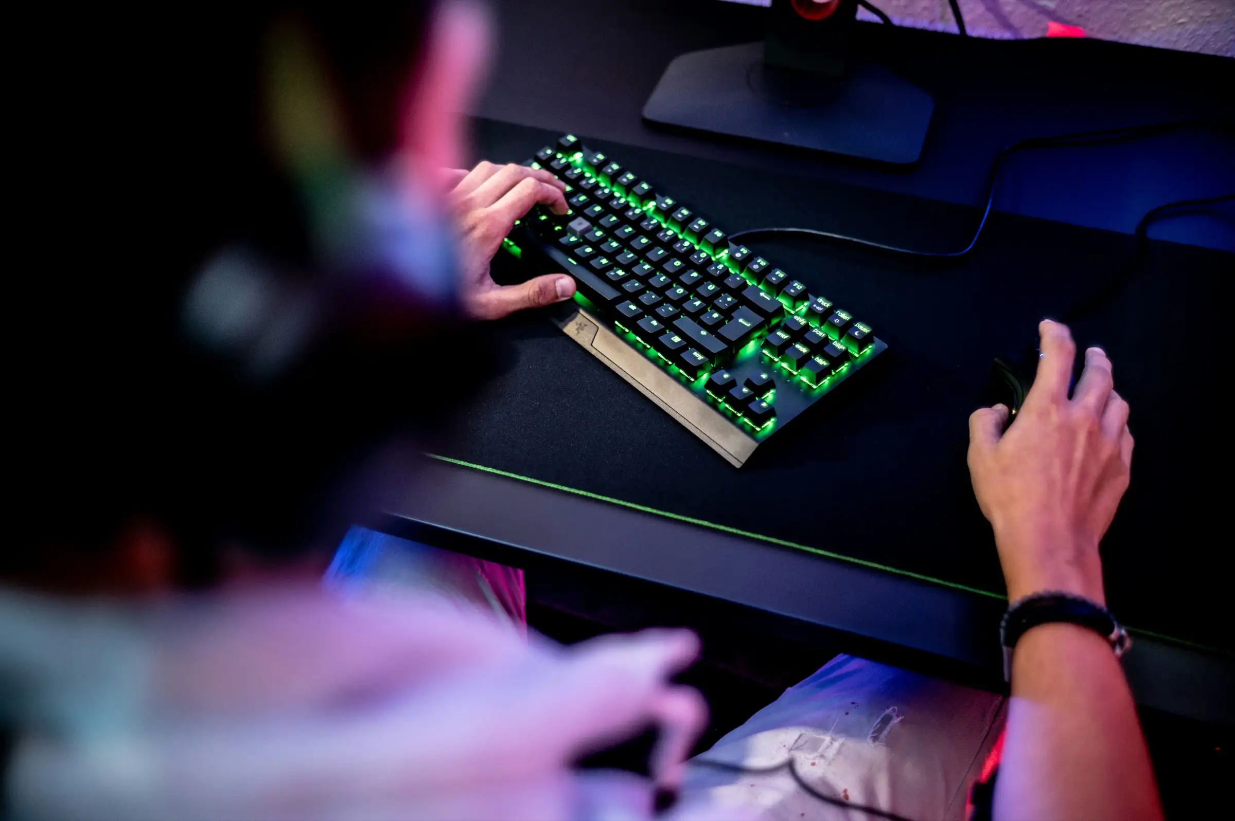 A player's hands on a backlit gaming keyboard and mouse